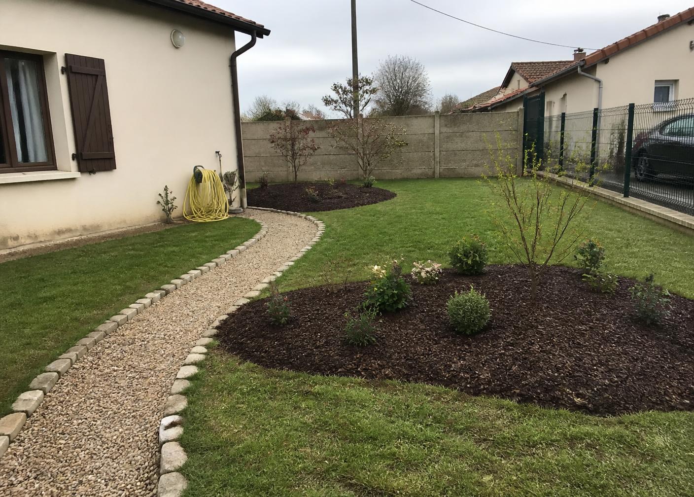 Jardin d'agrément neuf avec pelouse, allée en gravier bordée de pavés et massifs paillés